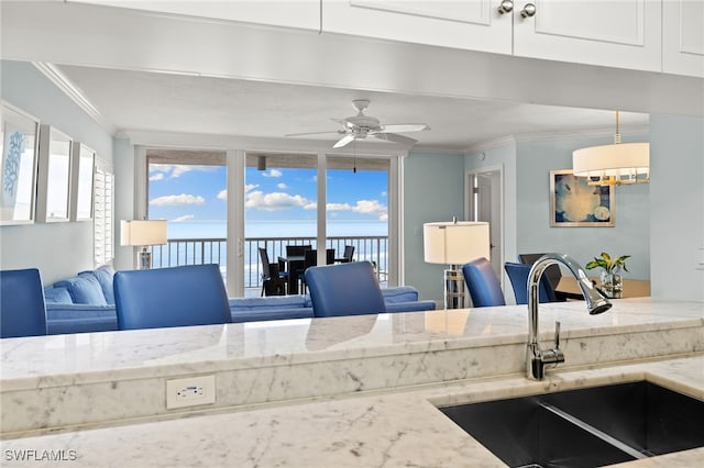 kitchen with crown molding, white cabinets, decorative light fixtures, and a sink