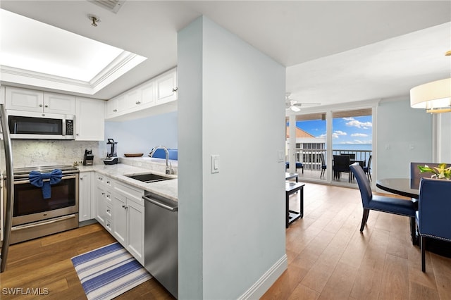 kitchen with appliances with stainless steel finishes, light countertops, a sink, and white cabinetry