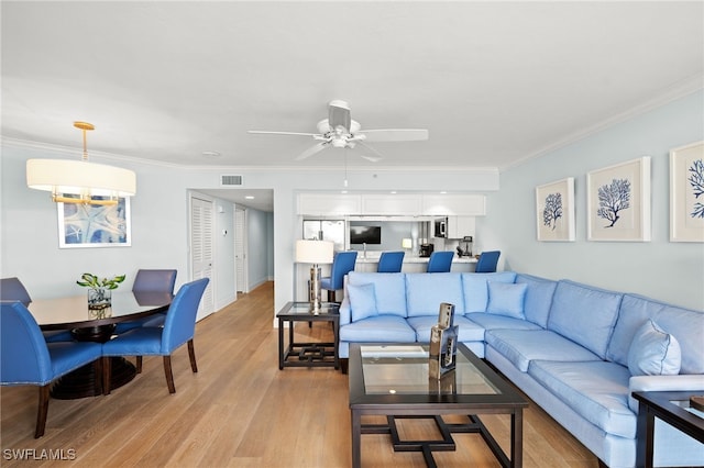 living room featuring light wood finished floors, a ceiling fan, visible vents, and crown molding