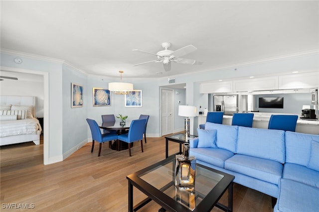 living area with light wood-style floors, crown molding, visible vents, and a ceiling fan