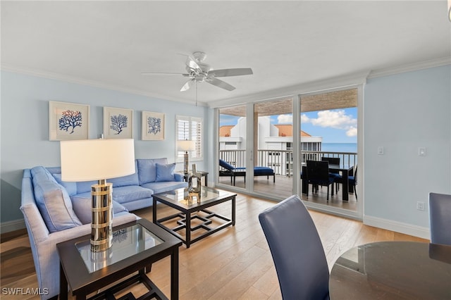 living area with a ceiling fan, baseboards, crown molding, and light wood finished floors