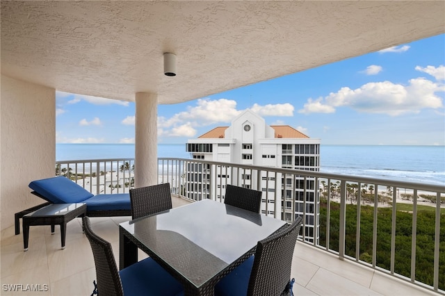 balcony with a beach view, outdoor dining area, and a water view