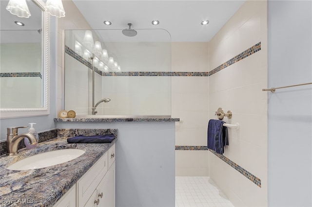 bathroom featuring a tile shower, tile patterned flooring, and vanity