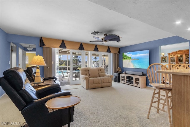 carpeted living room featuring ceiling fan and a textured ceiling