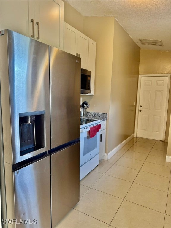 kitchen with light stone countertops, white cabinets, stainless steel appliances, and light tile patterned flooring