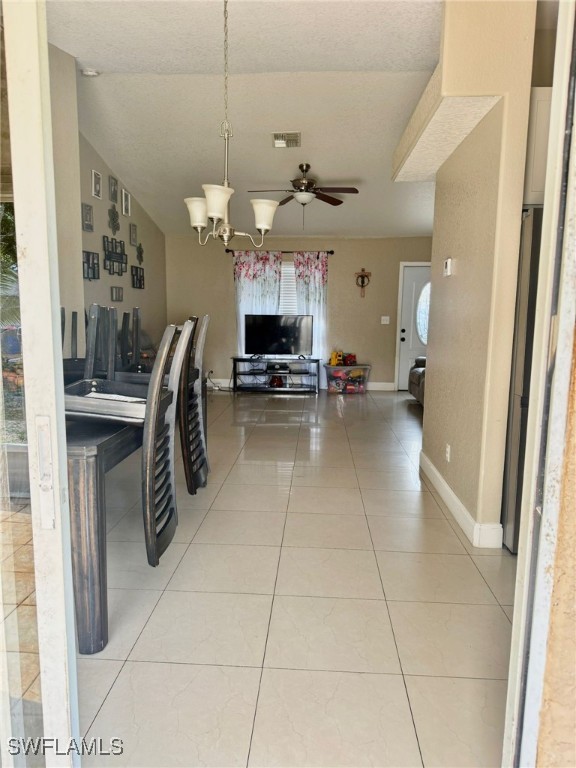 dining space featuring tile patterned flooring and ceiling fan with notable chandelier