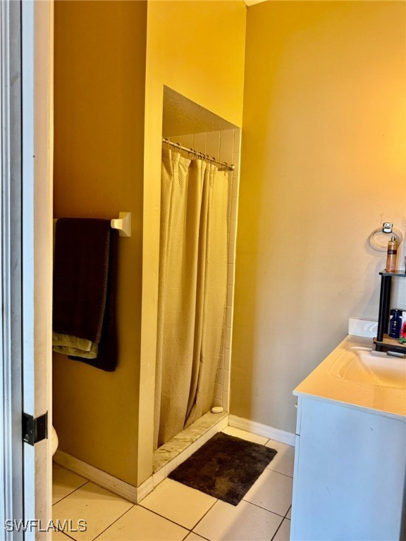 bathroom with walk in shower, vanity, and tile patterned flooring