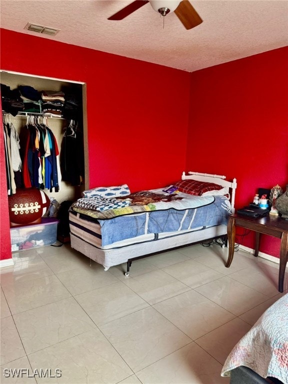 bedroom with ceiling fan, a closet, tile patterned floors, and a textured ceiling