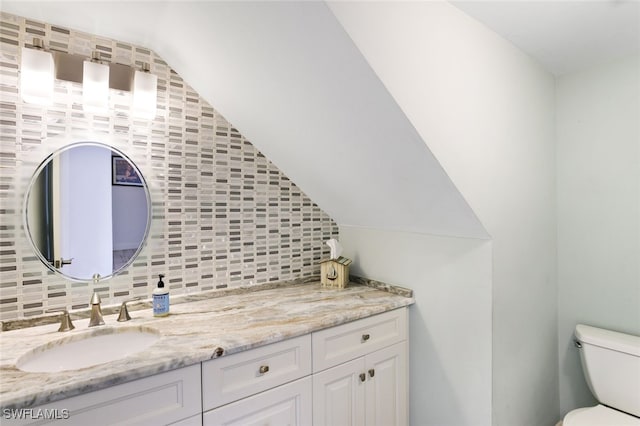 bathroom with vanity, toilet, backsplash, and vaulted ceiling