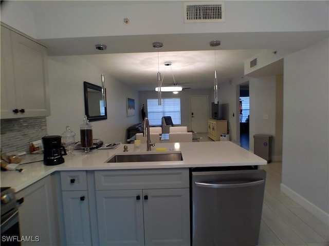 kitchen featuring pendant lighting, dishwasher, backsplash, white cabinets, and sink