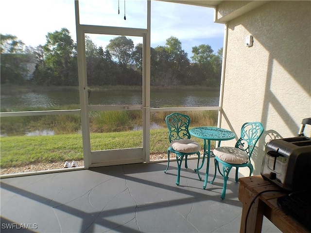 sunroom featuring a water view