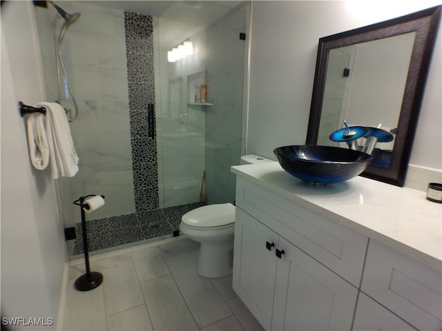 bathroom featuring tile patterned flooring, vanity, toilet, and a shower with door