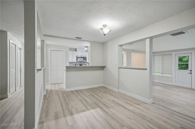 unfurnished room featuring light hardwood / wood-style floors and a textured ceiling