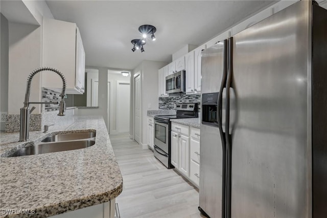 kitchen with tasteful backsplash, sink, white cabinetry, light stone countertops, and appliances with stainless steel finishes