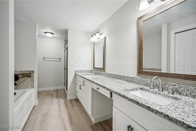 bathroom featuring hardwood / wood-style floors, vanity, and plus walk in shower