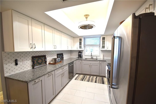 kitchen featuring decorative backsplash, appliances with stainless steel finishes, dark stone counters, sink, and light tile patterned flooring