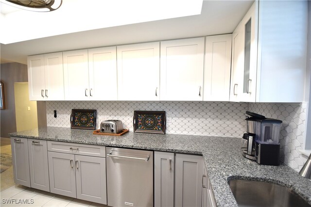 kitchen featuring backsplash, sink, light tile patterned floors, light stone counters, and white cabinetry