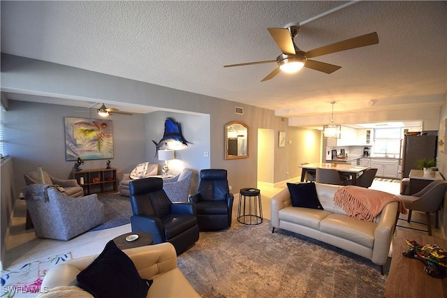 living room featuring carpet flooring, a textured ceiling, ceiling fan, and sink