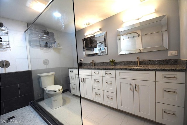 bathroom with tiled shower, vanity, and toilet