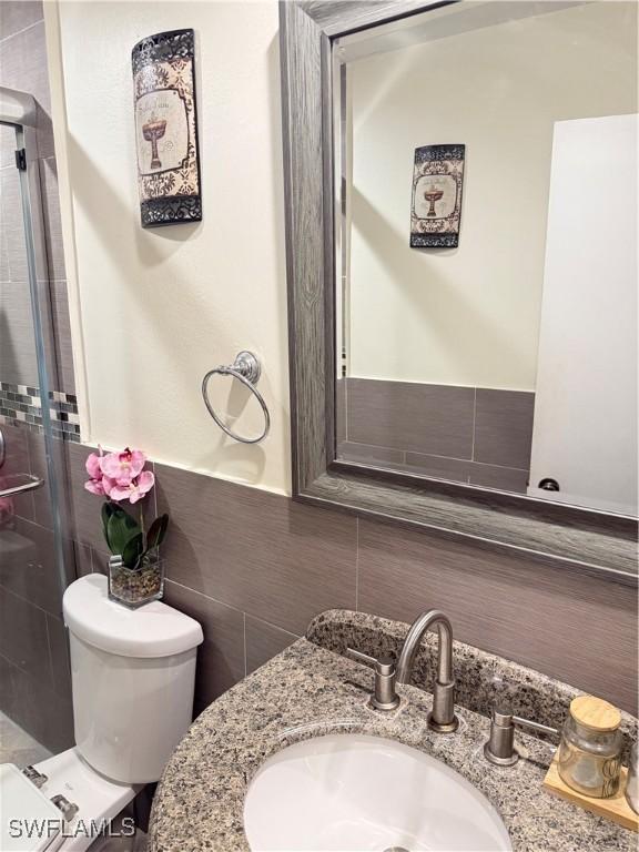 4207 Cindy Ave, Naples, FL 34112 - bathroom with vanity, a shower stall, toilet, and tile walls