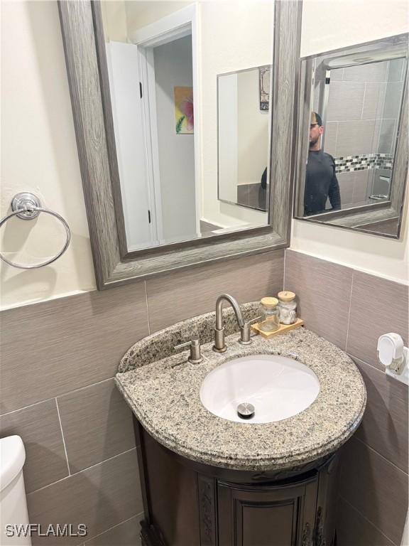4207 Cindy Ave, Naples, FL 34112 - bathroom with toilet, tile walls, wainscoting, and vanity
