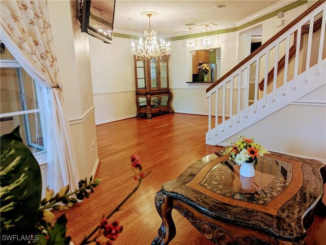 living room with hardwood / wood-style floors, a notable chandelier, and crown molding