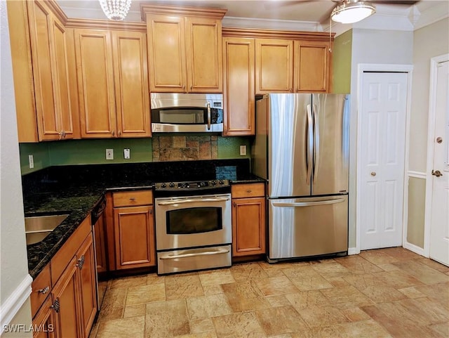 kitchen with appliances with stainless steel finishes, crown molding, dark stone counters, and sink