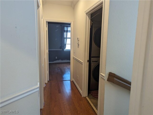 corridor with dark hardwood / wood-style flooring and stacked washer and dryer