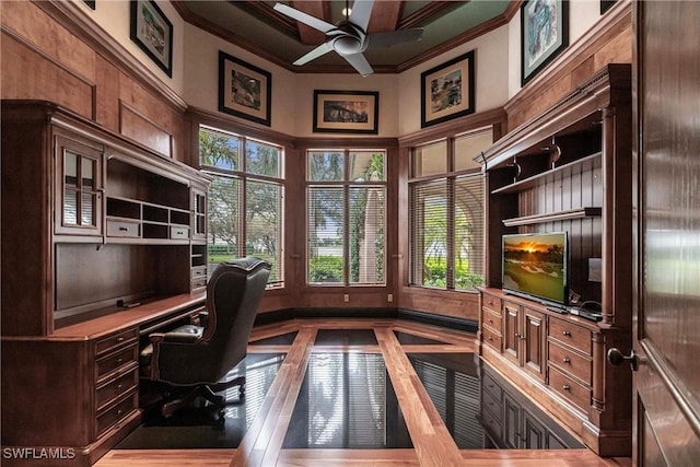 office space with ceiling fan, built in desk, crown molding, and a towering ceiling