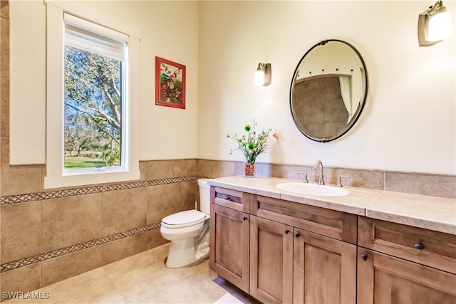 bathroom featuring toilet, vanity, tile patterned floors, and tile walls