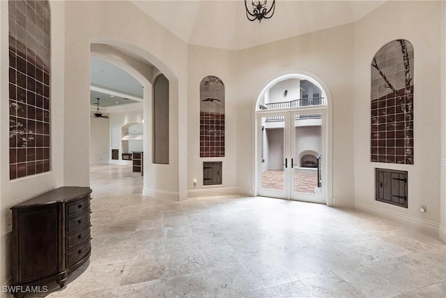 unfurnished living room featuring ceiling fan, a high ceiling, and french doors