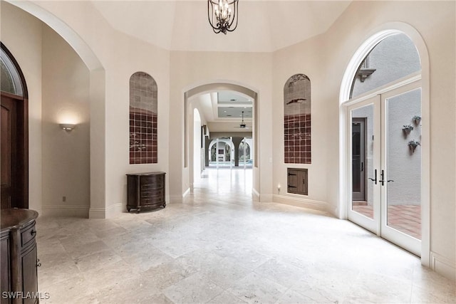 interior space featuring french doors, a towering ceiling, and a notable chandelier