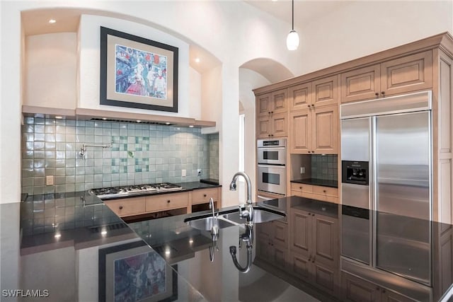 kitchen with pendant lighting, stainless steel appliances, tasteful backsplash, and sink