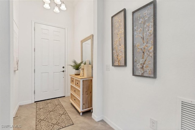 entryway with light tile patterned flooring and a chandelier