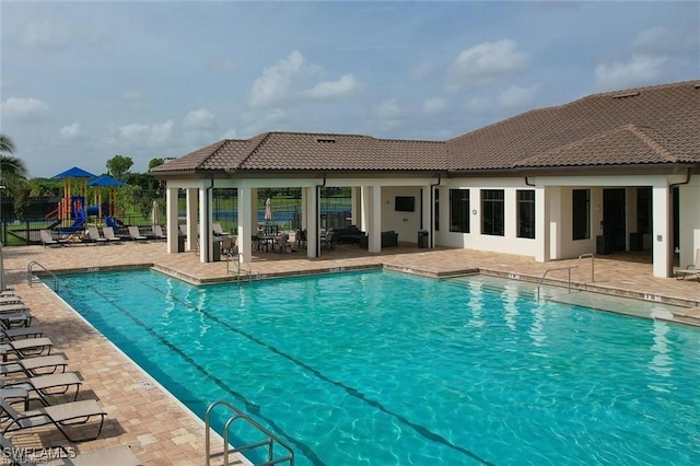 view of pool with a playground and a patio