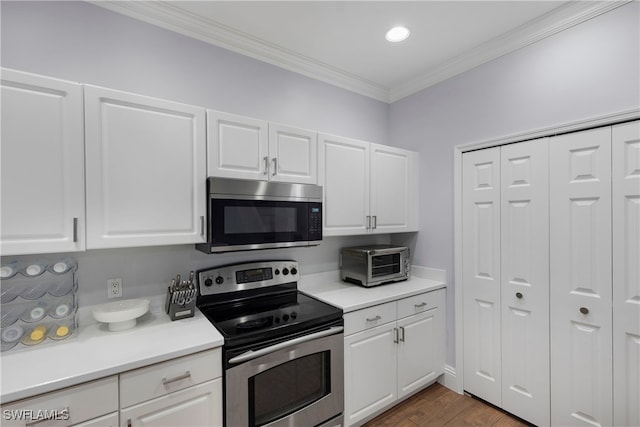 kitchen featuring crown molding, appliances with stainless steel finishes, white cabinets, and dark hardwood / wood-style flooring