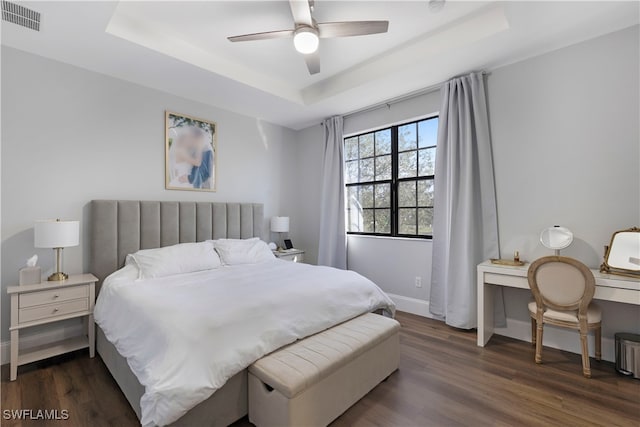 bedroom featuring dark hardwood / wood-style floors, a raised ceiling, and ceiling fan