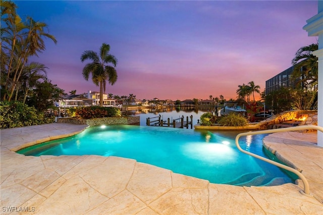 pool at dusk featuring a water view, a patio, and a dock