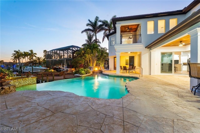 pool at dusk featuring a patio area and ceiling fan