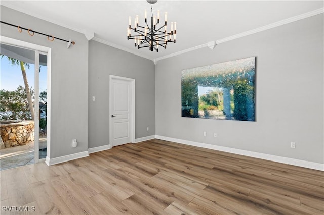 unfurnished room with hardwood / wood-style flooring, crown molding, and a notable chandelier