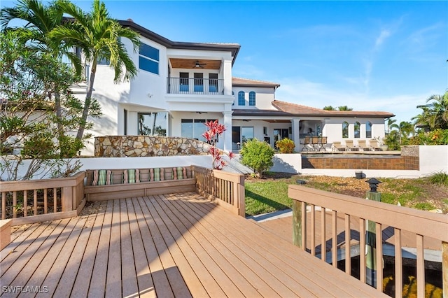 rear view of property featuring a wooden deck and a balcony