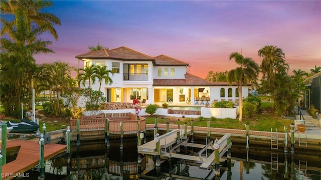 back house at dusk with a balcony and a patio area