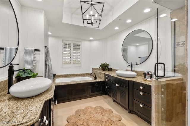 bathroom with vanity, a tray ceiling, wood-type flooring, an inviting chandelier, and plus walk in shower