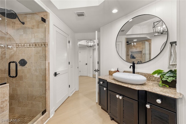 bathroom with a chandelier, wood-type flooring, vanity, and walk in shower