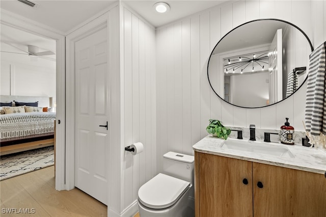 bathroom featuring ceiling fan, vanity, wood-type flooring, and toilet