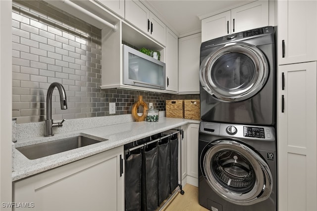 washroom featuring sink, cabinets, and stacked washer and clothes dryer