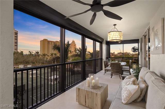 sunroom / solarium featuring ceiling fan with notable chandelier