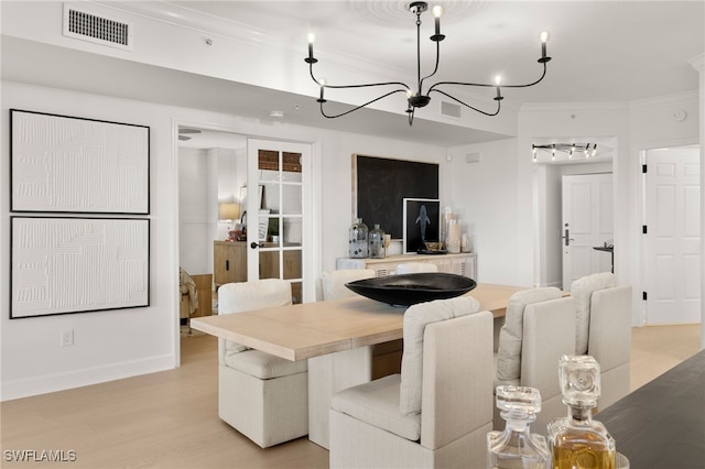 dining room with a chandelier, light hardwood / wood-style floors, and ornamental molding