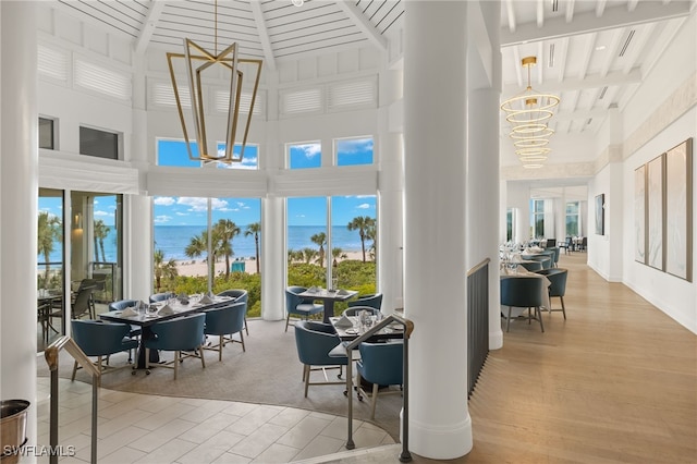 interior space featuring a healthy amount of sunlight, a water view, beam ceiling, and a chandelier