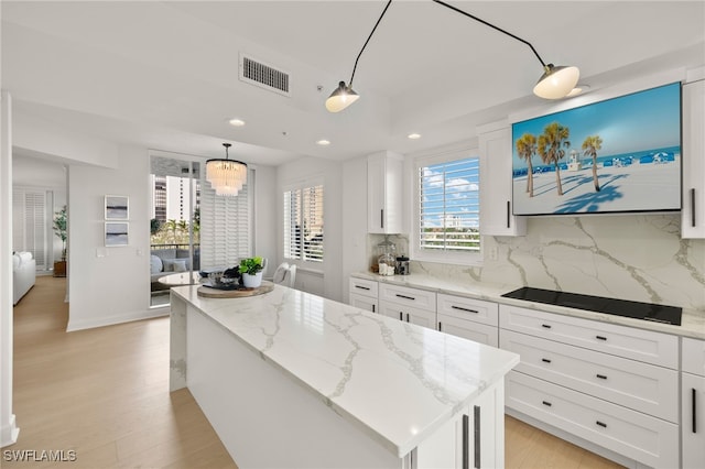 kitchen featuring pendant lighting, a kitchen island, white cabinetry, and tasteful backsplash